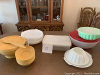 Wide view of all Tupperware items on table including bowls, molds, pie holders, and storage containers.