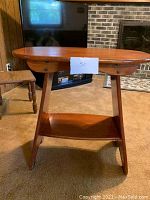 Full view of the wooden table, highlighting its height, shape and angled legs.