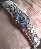 Close-up front view of the bracelet showing the central light blue faceted oval stone with clear center stone and filigree metalwork.