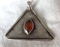 Front view of triangular sterling silver pendant with marquise carnelian stone set in the center on white cloth background.
