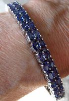 Close-up view of bracelet worn showing oval tanzanite blue colored stones in double-row sterling silver setting.