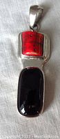 Front view of the sterling silver pendant with coral and onyx stones, showing the design and condition.