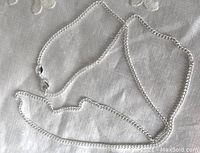 Full view of the silver curb link chain necklace laid out fully, showing clasp and chain links.