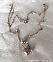 Full view of sterling silver chain with heart and sphere pendants laid on fabric background.