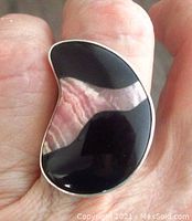 Top view of the crescent-shaped ring with rhodochrosite and black onyx stones, showing polish and color details.