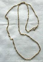 Full view of the vintage 10K yellow gold chain laid out on a white cloth, showing the length and clasp.