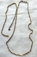 Full view of vintage 14K yellow gold rope chain necklace laid on white fabric surface, showing the entire length and delicate twisted rope design.