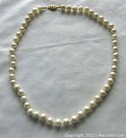 Full view of the 15 inch cultured pearl necklace laid out, showing the entire length and the clasp detail.