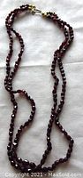 Full view of double strand garnet bead necklace, showing overall length and clasp.