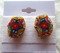 Front view of pair of vintage oval mosaic clip-on earrings with bright colored mosaic tile floral pattern set in twisted brass frames.