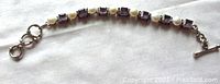 Full view of vintage sterling silver link bracelet with alternating amethyst stones and cultured pearls, laid out on white fabric showing toggle clasp.