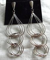 Front view of pair of vintage sterling silver dangling earrings showing delicate wire loop design and teardrop shape.