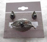 Front view of vintage sterling silver leaf brooch and matching earrings with hematite centers on display card.