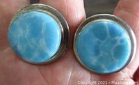 Close-up of the front of round vintage sterling silver earrings with large Larimar cabochon stones showing blue and white marbling.