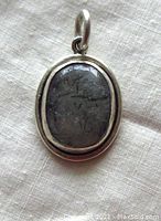 Front view of the oval tourmalinated quartz pendant set in polished sterling silver showing the stone inclusions and silver frame.