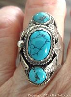 Front view showing three turquoise cabochons set in sterling silver with surrounding leaf design and rope border.
