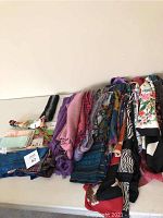 Various colorful scarves and neck ties laid out side by side, showing multiple fabrics and prints