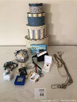 Displays four assorted nesting boxes stacked and multiple jewelry pieces arranged around them including necklaces, rings, earrings, and bracelets.