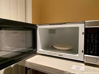Open view showing microwave interior with a glass turntable and light-colored tray inside.