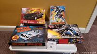 Four model kits displayed on a table, including 1995 Corvette ZR-1, Hot Bot Racer, Gundam Deathscythe action figure, and W-Gundam Zero Custom kit boxes.