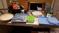 Overview of all kitchen items in the lot including storage jars, plates, trays, cutlery organizer, jello mold, cutting board