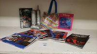 Overview of 5 Spider-man Marvel graphic novels, Disney Aladdin Adventures in the Cave of Wonders comic, Laura Croft Tomb Raider comic, and small tower model statuettes.
