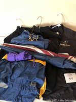 Top down view of various jackets, windbreakers and umbrellas with hangers visible
