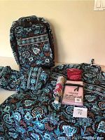 Front and top view of Java Blue patterned garment bag, rolling suitcase, and assorted travel accessories