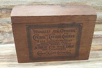 Wooden vintage cream cheese box showing front label and curved lid.