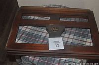 Front view of the Dexler wooden book stand placed on a plaid cloth surface showing the wooden slats and logo plaque.