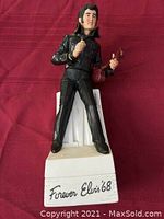 Front view of porcelain Elvis Presley decanter standing on white base labeled "Forever Elvis '68".