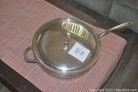Closed fry pan with lid on tablecloth, showing overall size and shape