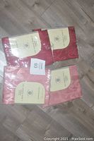 Four packages of napkins laid out on a floor showing two dusty pink and two brick red packs