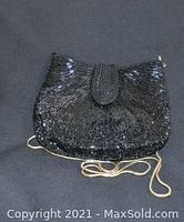Front view of the vintage black beaded evening bag with gold chain on dark background