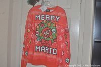 Front view of red Merry Mario sweatshirt showing the holiday graphic and text.
