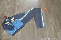 NWT Nike 2-piece baby boy jogging suit displayed on a wooden floor, showing jacket and pants with multicolor stripes and logo.