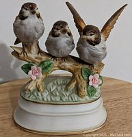 Front view of the porcelain music figurine showing three birds on a branch with pink flowers.