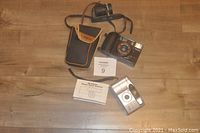 Two vintage 35mm film cameras along with black and brown Targus camera case and detachable neck strap, instruction manual also included