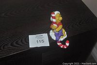 Winnie the Pooh stocking holder figurine placed on a dark wood surface, showing front angle with candy cane held by Winnie the Pooh.