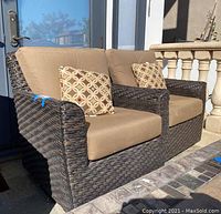 Front angle view of both wicker chairs with cushions and throw pillows