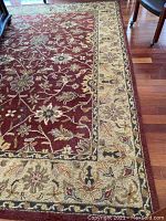 Corner view showing burgundy field with central floral motif and beige floral border