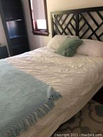 Full view of the full size bed frame assembled with mattress, white linens, and green pillow for display