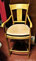 Single oak wood pub stool with rush seat and tan leather cushion showing curved back and armrests