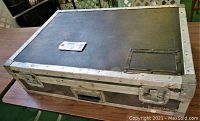 Top and sides of a black rectangular hard shell road case on a table showing scratches and wear.