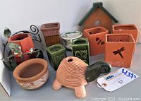 Overview of ceramic garden pots, votive candle holders, and decorative planters in various shapes and colors, including terracotta, green, white, and a turtle shape.