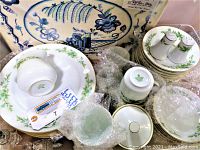 View of various plates, cups, saucers, bowls, and boxed placemats with bubble wrap protective packaging.