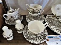 View of cups, saucers, sugar bowl, salt and pepper shakers, and plates in brown and white Royal Mail Ironstone pattern.