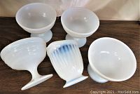 Top view of four white sherbet dishes on a wooden surface, showing their rounded bowls and pedestal bases.
