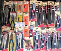 Full view of 23 packaged hand tools including pliers, screwdrivers, sockets, and grinding stone kit arranged flat on surface
