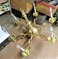 Top-side angle showing entire 6-arm solid brass chandelier with candle-style bulbs and polished finish.